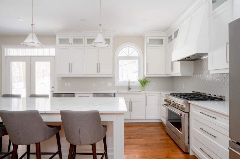 Renovated kitchen with modern white cabinetry, hardwood floors, and stainless steel appliances by Odyssey Custom Contracting Ltd.