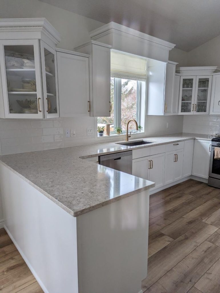 Renovated kitchen with modern white cabinetry and marble counters by Odyssey Custom Contracting Ltd.