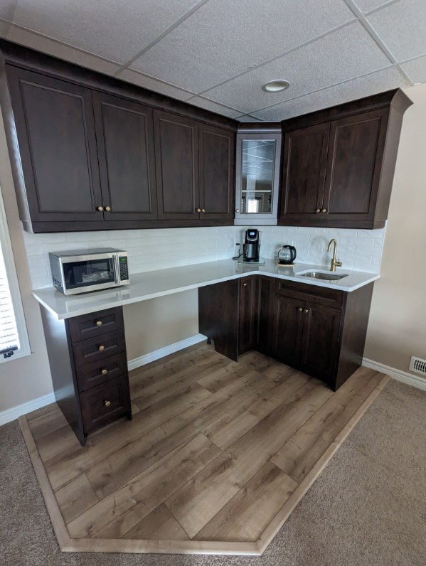 Renovated kitchenette with dark oak cabinetry and white marble countertop by Odyssey Custom Contracting Ltd.
