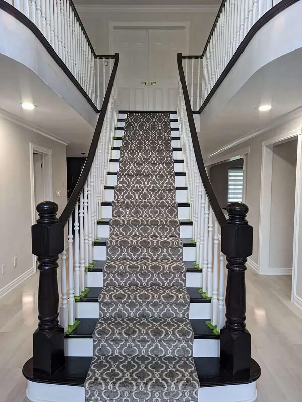 Custom staircase renovation with dark wood banister and geometric patterned carpet runner by Odyssey Custom Contracting